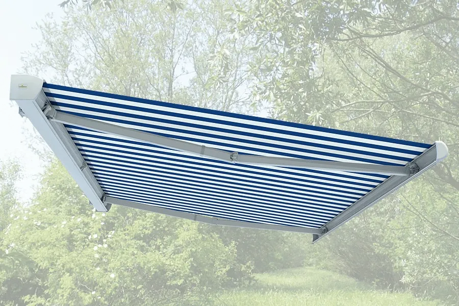 Gestreifte Millenium Markise erstreckte sich vor einem verschwommenen Hintergrund mit Bäumen.