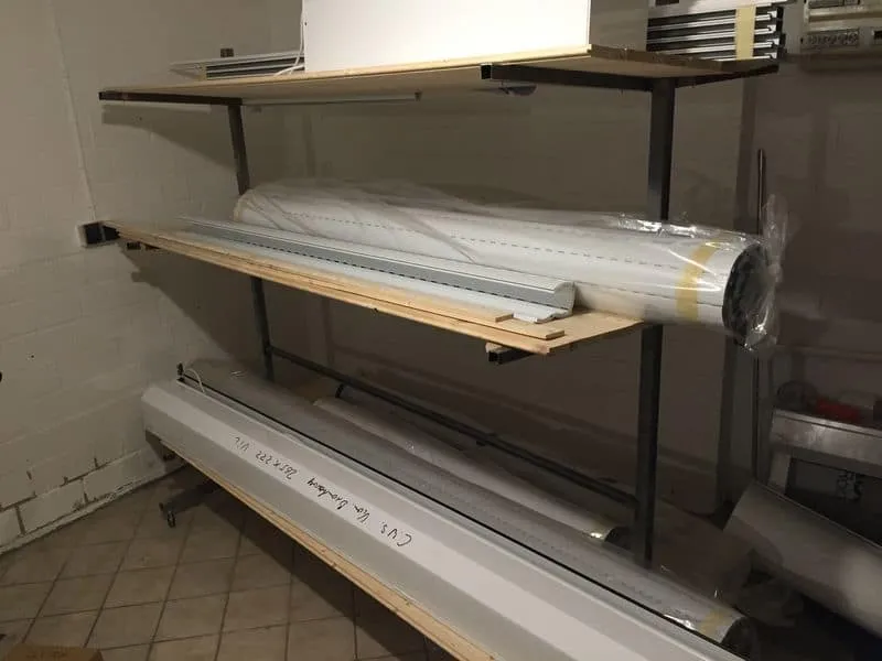 Metallregal mit Leuchtstofflampen und langen Röhren, aufbewahrt in einem Raum mit Fliesenboden.